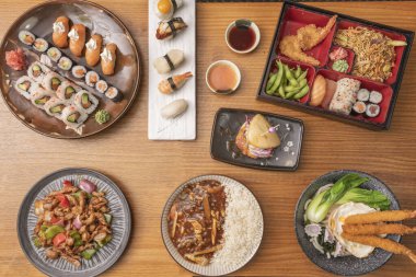 Teriyaki tavuğu, havuç ve avokado serpiştirilmiş, dikdörtgen porselen bir tabağa siyah susam tohumları serpiştirilmiş.