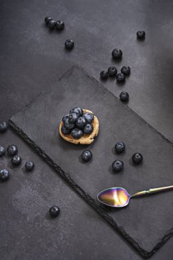 Eski bir binicinin deri arka planında yaban mersinli kompozisyon ve zamanın patinajını gösteren bir kalay kaşığı