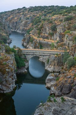 Alacakaranlıkta baraj gölünde yakındaki kasabaların ışıkları yanmaya ve karanlık suları yansıtmaya başlıyor.