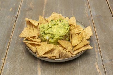 Farklı et, peynir ve salsa tabaklarıyla karışık nacholar büyük bir tabakta sunuluyor.