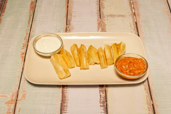 Ev yapımı kızarmış yuca, çıtır çıtır ve yumuşak bir merkez üzerine sarımsak tuzu ve taze doğranmış maydanoz serpiştirilmiş.