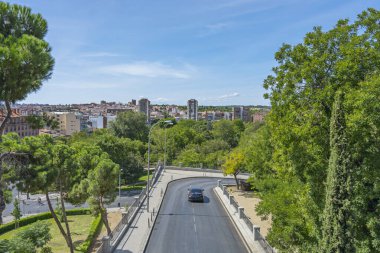 Alçak binalar ve gri şehir profilini zar zor değiştiren birkaç sıradan ağaçla dolu bir cadde.