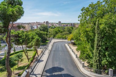 İkincil şehir yolu birkaç dağınık ortak ağaçla birlikte asfalt yol kenarına yakın.