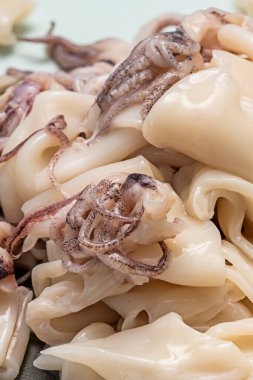 Yeni temizlenmiş mürekkep balığı parçaları farklı kesiklerini gösterir: bazıları halka şeklinde, bazıları şerit halinde, ve dokunaçlar da tüm enayileriyle birlikte.