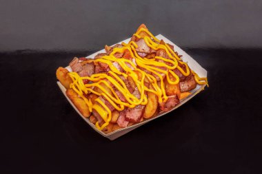 Rahatlatıcı bir tabakta çapraz dilimlenmiş sosisler, çıtır patatesler ve bir tutam kremalı sosla mükemmelliğe altın kahverengiler yer alır.