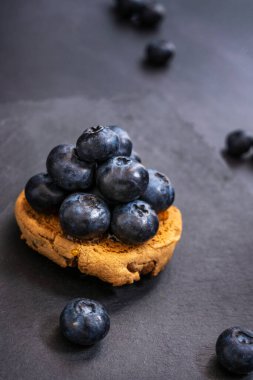 Ezilmiş bir yabanmersininden sızan mor sıvı yansıtıcı siyah yüzey boyunca yavaşça yayılan canlı bir havuz oluşturur.