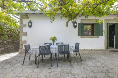 Açık meşe yemek masası bir verandaya yerleştirilmiş doğal bir taş cephesi ve antik zeytin ağaçlarının yansıttığı bir gölge.