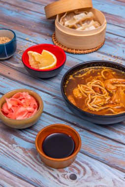 Tayland usulü köri, hindistan cevizi sütü ve kil kapta limon otuyla kızartılmış karidesli erişte.