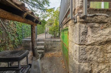 Dış çevre geçidinde, kaymayan, alevli granit kaldırımlar ve doğal taş duvara entegre banklarla görsel bir tur.