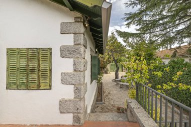 Granit asfalt ve birleşik bankların olduğu taş duvarın yanında olgun gül çalılarından oluşan yükseltilmiş bir yatak.