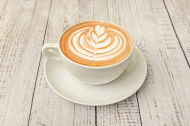 Kapuçino, kakao tozu ve tarçınla kaplanmış kırsal seramik bir fincanda doğal ahşap saplı..