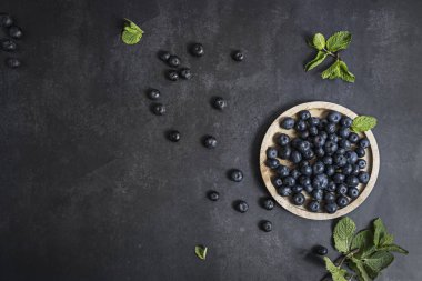 Yaban mersinlerinin siyah arkaplana karşı asimetrik dizilişi, her böğürtlenin karanlık evrende bir noktayı temsil ettiği yıldız takımyıldızlarını çağrıştırıyor.