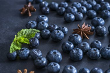 Sütlü siyah yüzey yaban mersinlerinin küresel şekillerini incelikle yansıtıyor ve kompozisyonda iki kat hayalet etkisi yaratıyor..
