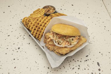 Yumurtalı çıtır tavuk burger, kızarmış domuz pastırması ve haşlanmış çöreğin üzerinde ev yapımı Hollandaise sosu.