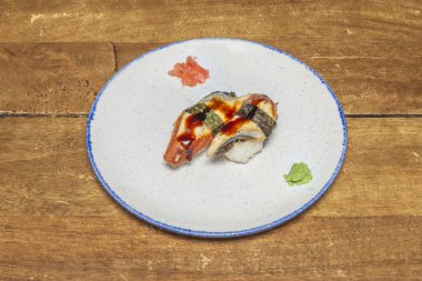 Unagi yılanbalığı nigiri, yanında bir dilim ızgara yılan balığı ve yanında da tatlı tara sosu..