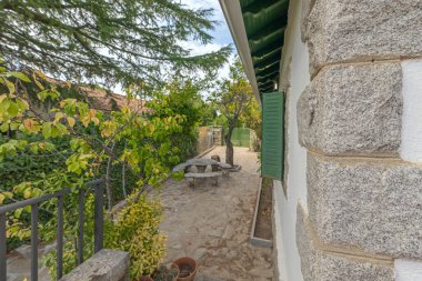 Granit bir masa ve huş ağacının benekli gölgesinin altında ahşap banklar olan yemek takımı.