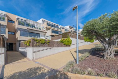 Sayısız terası ve ağaçlı ortak alanları olan bir konut kompleksinin ön cephesi ve girişi