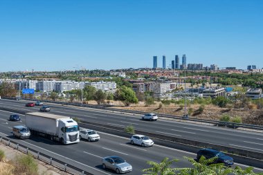 Yoğun şehir yolu sabah trafiğinde kırmızı ışıkta duran uzun sıra araçlarla dolu.