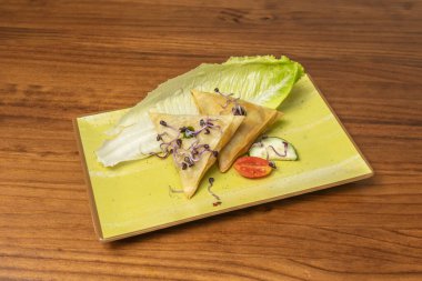 Mükemmel bir eşlikçi: yeşil kişniş sosu ve tatlı turşu bu samosanın etrafını sarar, daldırılmaya ve tadını arttırmaya hazırdır.