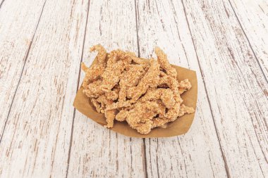 Panko ekmek kırıntısı ve baharat karışımına bulanmış tavuk şeritleri, altın kahverengiye kadar kızartılmış ve kıvırcık salata ve çiftlik sosuyla servis edilmiş.