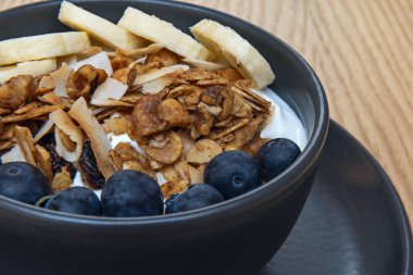 Sahne, elma dilimleri, mor üzümler ve üzerine bir şerit sıvı karamelli süzme peynir serpiştirilmiş bademlerle sağlıklı bir hoşgörü sunuyor.