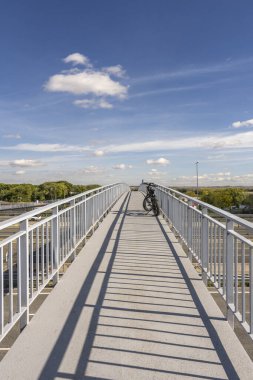 Geometrik çizgileri izole eden minimalist bir kompozisyon ve açık bir gökyüzüne karşı üst geçit yapısının tekrarlayan desenleri.