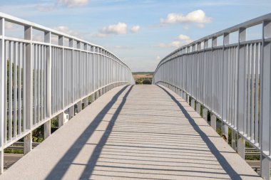 Beyaz yapının iskeleti tarafından oluşturulan kaldırıma bir ışık ve gölge oyunu yansıtılır, herhangi bir insan varlığından yoksun bir çekimde.