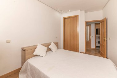 Minimalist yatak odası, 140 cm 'lik yatak odası, deri yatak başlığı, eklemli duvar lambaları ve çerçevesiz dairesel ayna.