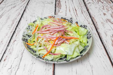 Bak, dilimlenmiş havuçlu choy salatası, kırmızı dolma biber, fasulye filizi ve ızgara tavuk şeritleri, zencefil, sarımsak ve susam yağı ile kaplanmış.