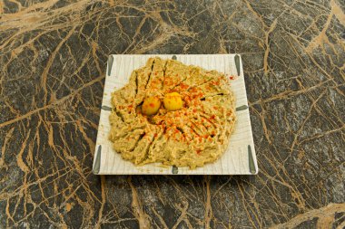 Mükemmel bir daire şeklinde dizilmiş ve nane yaprakları, siyah zeytinler ve tatlı kırmızı biberle süslenmiş baba ghanoush 'un zarif bir sunumu..