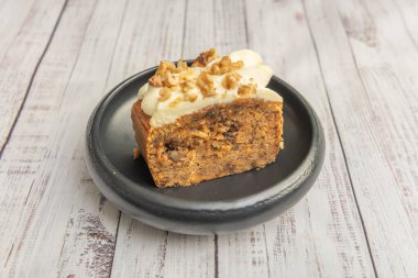Cevizli ve kuru üzümlü havuçlu kek, üzerinde bol krem peynirli krema, karamelli cevizlerle süslenmiş ve tarçınlı.