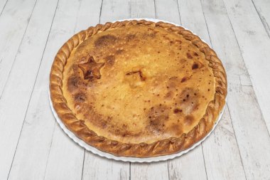 Pirzola ve şalgam yeşili empanada, et ve sebzeleri taze şalgam yeşil yapraklarıyla çevrili merkezi bir kesikte dekorasyon olarak gösteriyor.