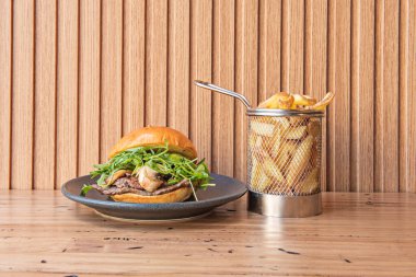 Kalın, sulu etli bir köfte ile klasik bir burger, tamamen erimiş çedar peyniri ile kaplanmış ve çıtır çıtır altın patates kızartması üzerine sızıyor.