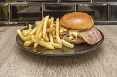 Bir gurme burger bol porsiyon erimiş çedar peyniri ile taçlandırılır, kremsi dokusuyla üst taraftaki kıtır pastırmayı tamamlar.