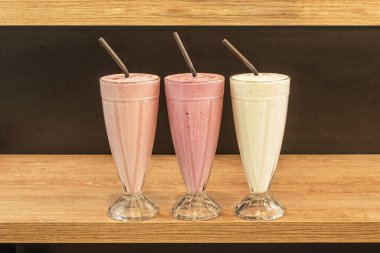 Meşe ağacından bir rafta siyah pipetli çeşitli tatlardan oluşan bir sıra meyve püresi.