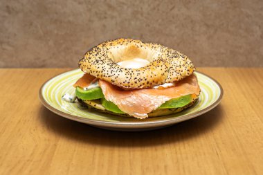 Açık yüzlü bir simitte bol miktarda ev yapımı gravlax somon balığı, krem peyniri, ağzında patlayan somon yumurtası ve taze doğranmış soğan bulunur.