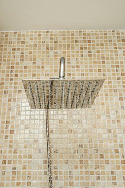 Modern kare krom kaplamalı duş başlıklarının yerleştirildiği, su tesisatını mobilyalarla sorunsuz bir şekilde birleştiren, mat beyaz kapılı bir banyo dolabı.