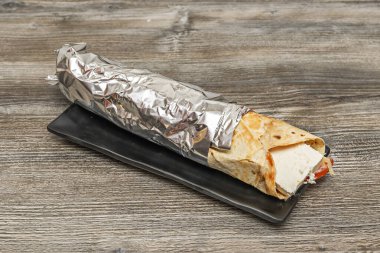 Yoğurt ve bitki soslu biftek shawarma, pide ekmeğinde marul, domates, soğan ve acı sos ile servis edilir..