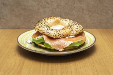 Açık yüzlü bir simitte bol miktarda ev yapımı gravlax somon balığı, krem peyniri, ağzında patlayan somon yumurtası ve taze doğranmış soğan bulunur.