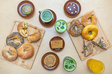 İçinde füme somon, salatalık ve kapari bulunan modern bir kompozisyon, bir sürahi mimoza ve mermer masaya yayılmış bir gazete.