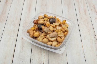 Dörtgen, şeffaf, içi çiğ, beyaz bademlerle dolu, pürüzsüz dokularını ve açık kahverengi renklerini gösteren, abur cubura hazır bir plastik kap.