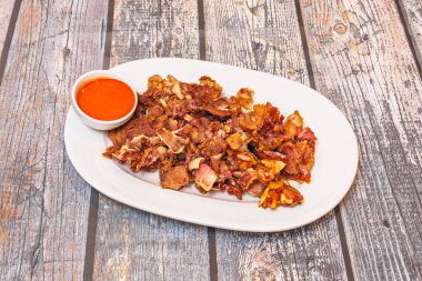 Domuzun kulağının kompleks dokusunu ön plana çıkaran bir yakın plan: şeffaf kıkırdağı, jelatinli eti ve karşı konulamaz çıtır çıtır, hafif yanmış kenarları..