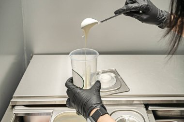 Uzun saçlı bir kadının elleri kremalı milkshake hazırlıyor.