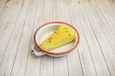 Altın kabuklu, kremalı, ahududu soslu ve siyah tabakta taze nane yapraklı üçgen New York peynirli keki.