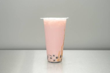 Taro köpüklü çayının bir kenar görüntüsü, tepesindeki koyu bir gölgeye dönüşen sütlü leylağın belirgin katmanlarını gösteriyor..