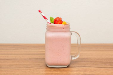 Papaya, çilek ve doğal yoğurttan yapılan yumuşak somon balığı renkli bir meyve suyu, cam sürahiyi sıvı ayrımı eksikliğinden belli olan dekoratif çizgilerle doldurur.