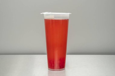 A glass of red berry bubble tea, with a deep garnet red color