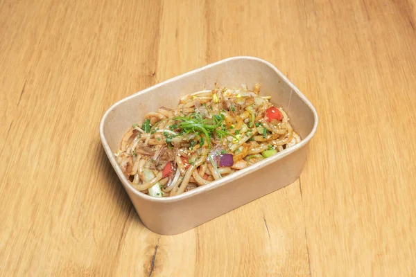 Klasik bir karton paket, ağzına kadar Çin eriştesi, kızarmış karides, bezelye ve erişteyle karıştırılmış çırpılmış yumurta ile dolu..