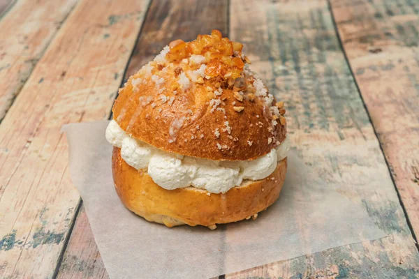 Krem rengi halka şeklinde bir pasta ana malzemesinin yanında sunuluyor, tüm pastayı ve fazladan bir kase kremayı gösteriyor, daha fazla dolgu malzemesi ekleme olasılığını öneriyor..