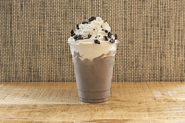 Uzun bir bardakta servis edilen kalın, soğuk bir çikolatalı milkshake, üzerine bol miktarda krema dökülmüş, kenarlardan nazikçe dökülen..